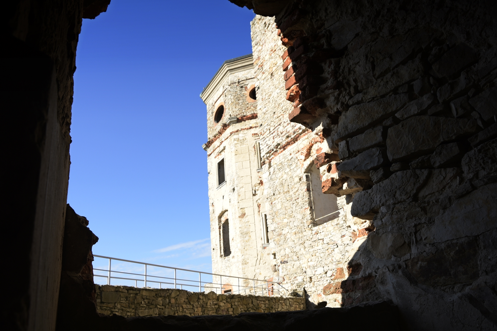 Wieża zamku Krzyżtopór widziana przez zrujnowane okienko świętokrzyskiego zamku.