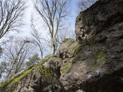 Potężny głaz widziany od dołu, z widokiem na niebo w Kamień Michniowski.