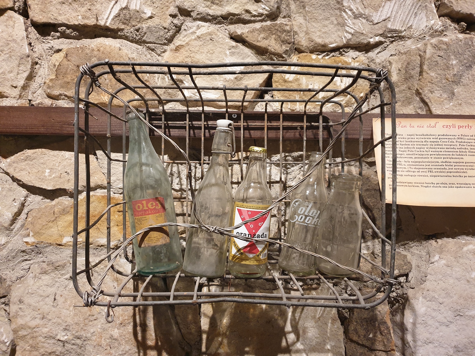 Fragment wystawy w atrakcji Opatowa, czyli podziemiach - butelki w koszyku.