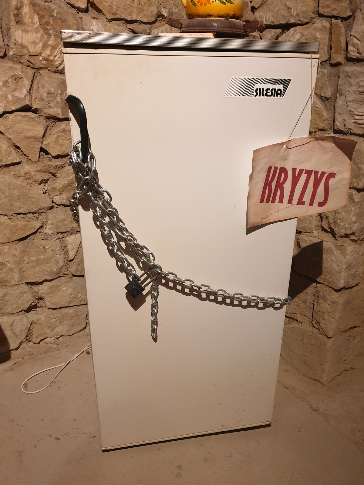 Lodówka zabezpieczona łańcuchem z kłódką i kartką kryzys - wystawa w atrakcji Opatowa, czyli w tutejszych podziemiach.
