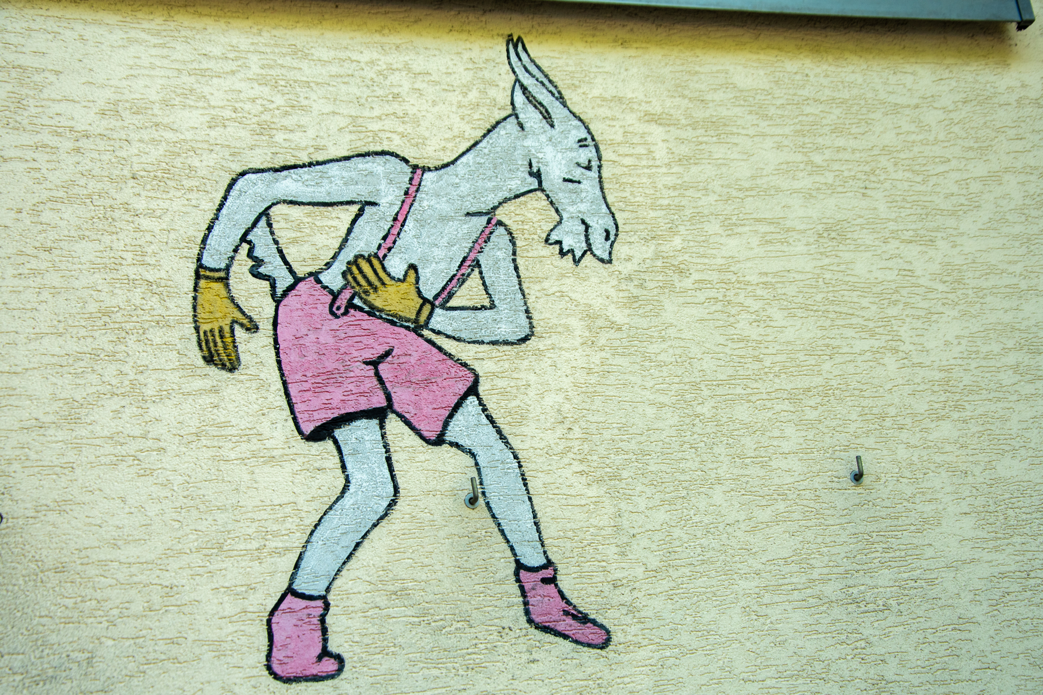 Koziołek Matołek namalowany na murze domu, kłaniający się w pas.