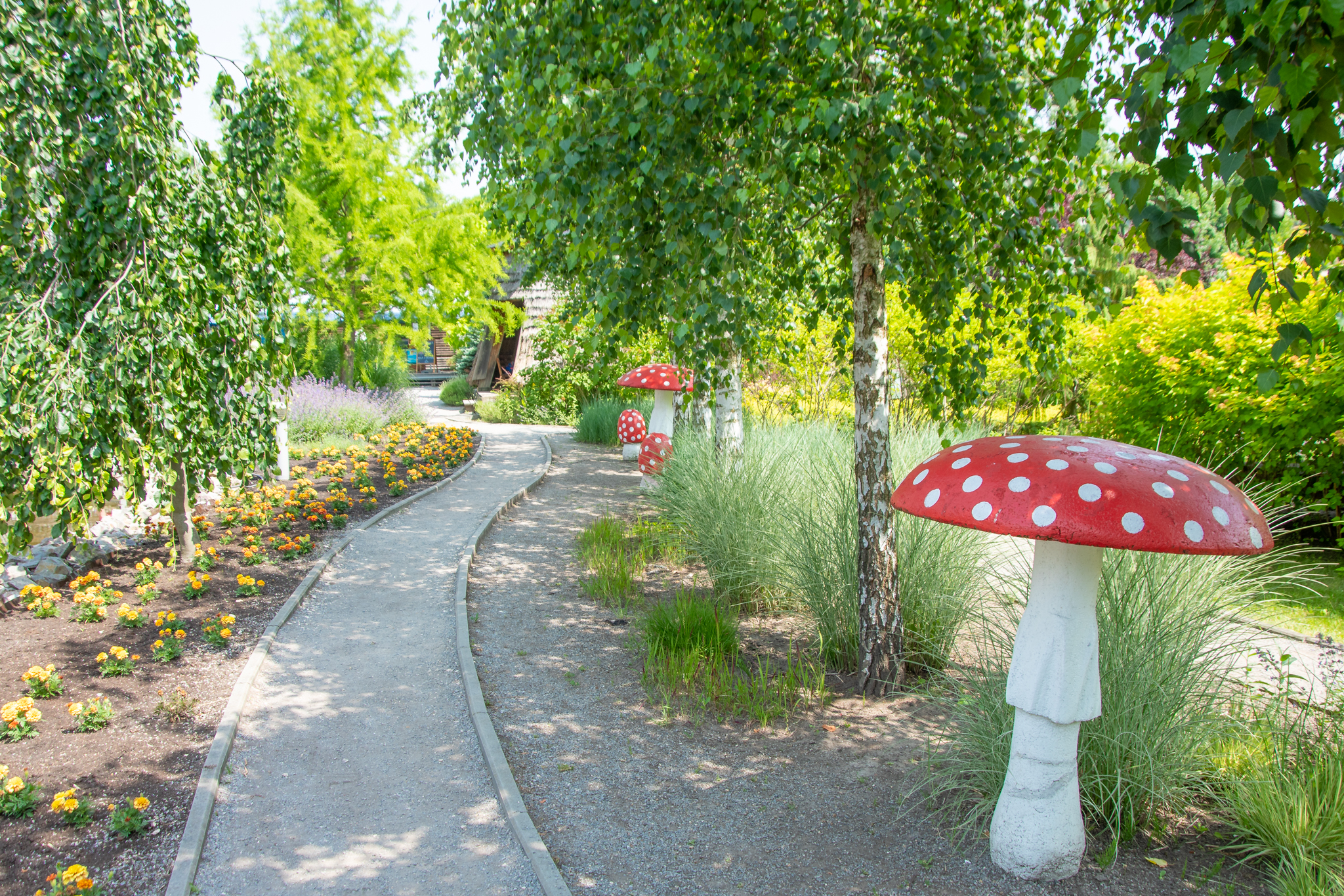 Duże plastikowe muchomory przy ścieżce w ogrodzie w Centrum Bajki w Pacanowie.