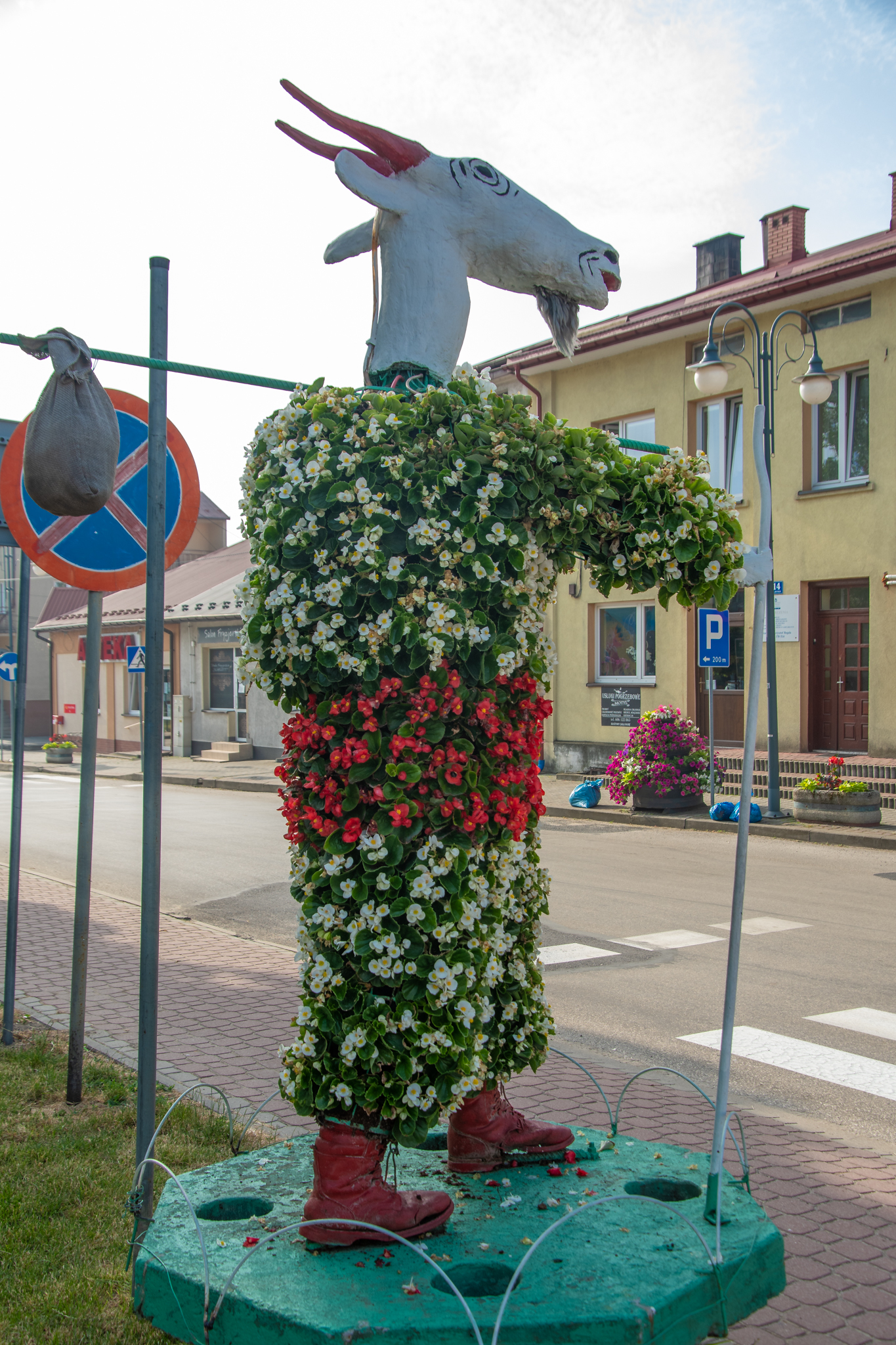 Duża figura koziołka Matołka zrobiona ze styropianu i cała obrośnięta kwiatami.