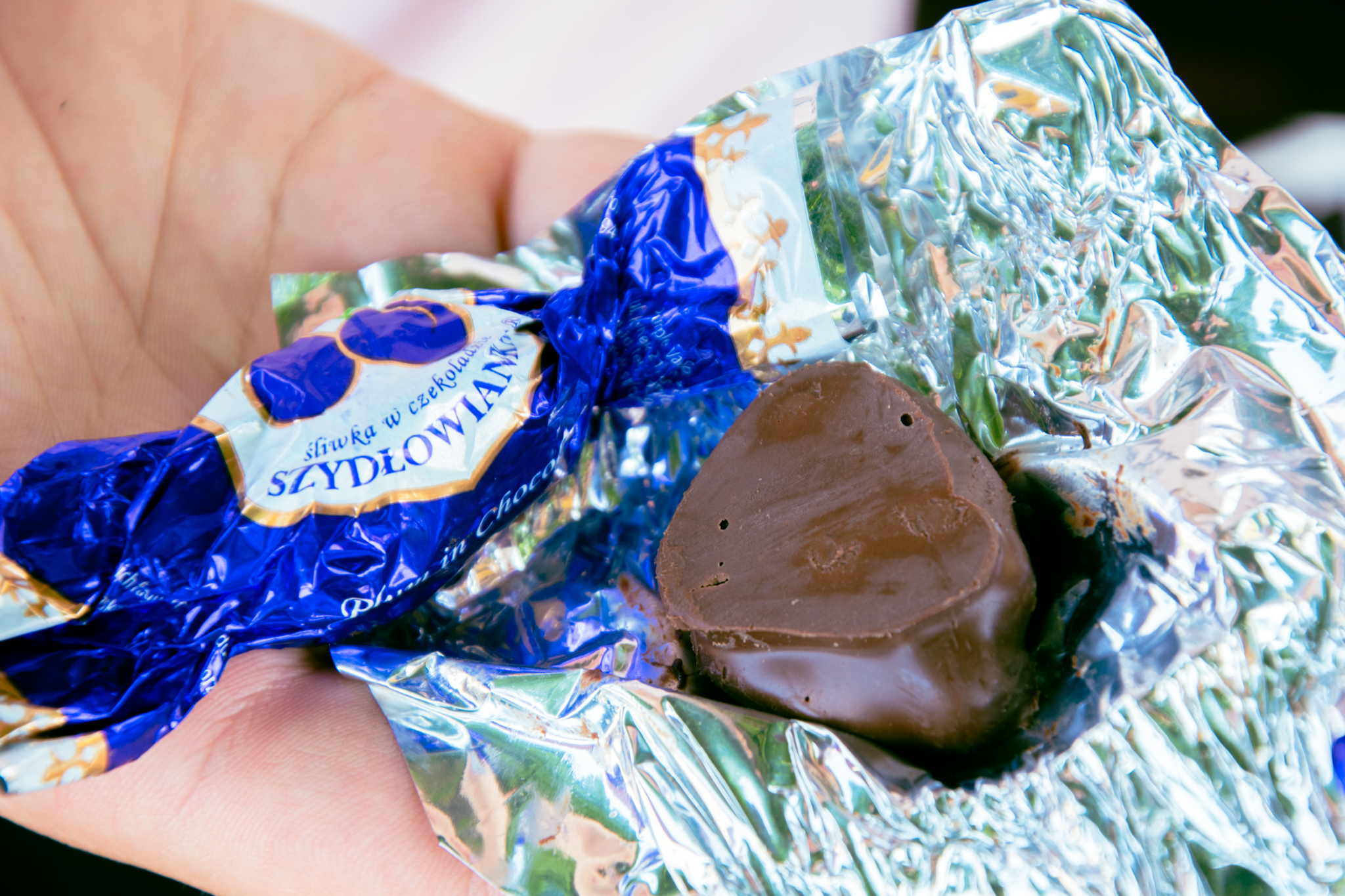Cukierek śliwka w czekoladzie od firmy Szydłowianka, rozpakowany.