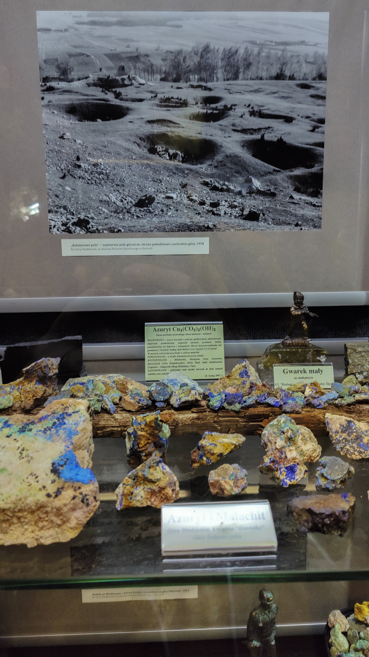 Zdjęcie z dziurami jak na księżycu, pod nim kolorowe kamienie na wystawie w Muzealnej Izbie Górnictwa Kruszcowego w Miedziance.